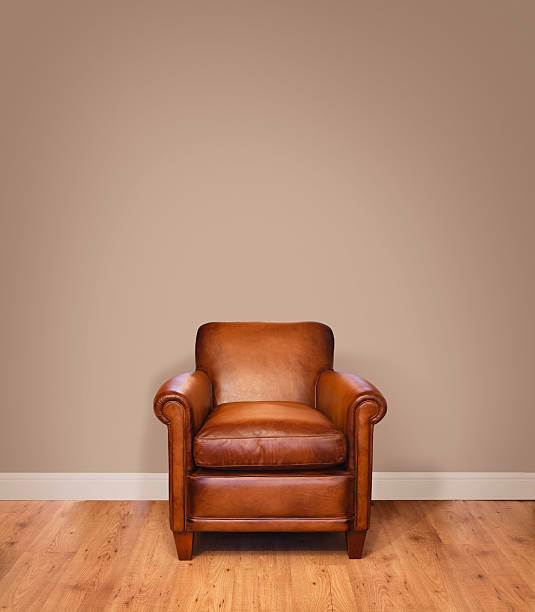 Modern interior Leather armchair on a wooden floor against a plain background wall with lots of copyspace. The wall has a clipping path. leather couch stock pictures, royalty-free photos & images