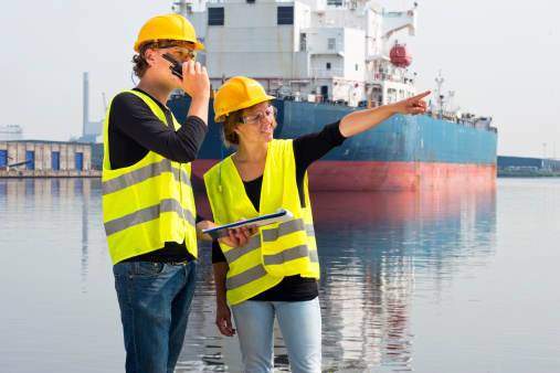 Two technology students discussing an assignment during an internship on site at an industrial harbor