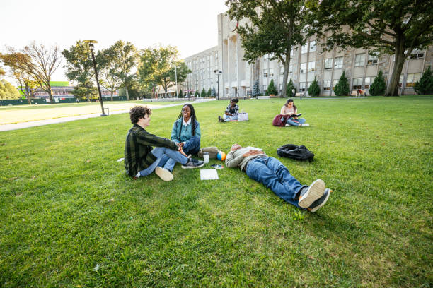 istock Group of diverse students in campus outdoors, sitting on lawn and enjoying snack after lectures 1774056938