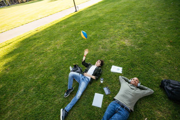 istock Group of diverse students in campus outdoors, sitting on lawn and enjoying snack after lectures 1774058286