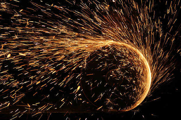 Metalworker using a welding machine while wearing a protective helmet to shield from the bright arc.