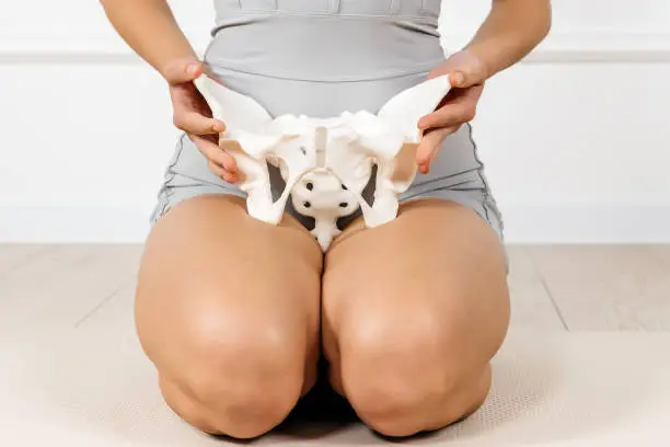 Photo of Close-up of the female pelvis in the hands of an athletic, healthy woman. Gynecology, women's healthcare and medicine and healthy body concept.