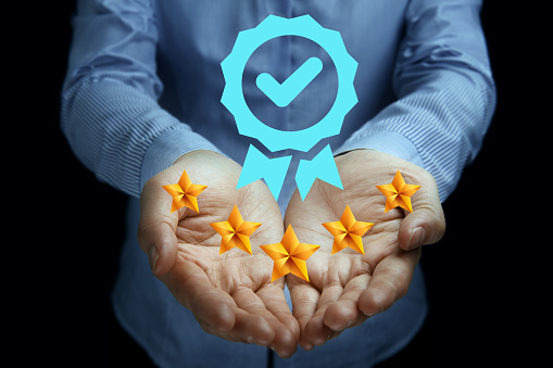 An individual showcases a holographic badge of approval with a check mark and five golden stars, representing top-tier quality, excellence, and satisfaction in a service or product. The image captures the essence of quality assurance and customer satisfaction in a visually appealing manner.