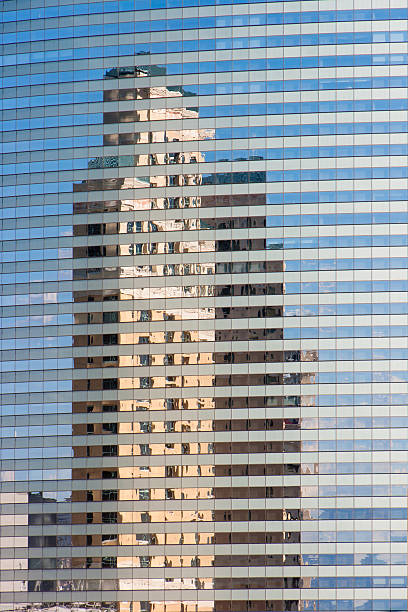 tall skyscraper reflected in building mirror glass wall stock photo