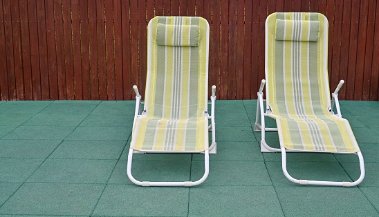 Two green sun loungers are a bit worn out.
