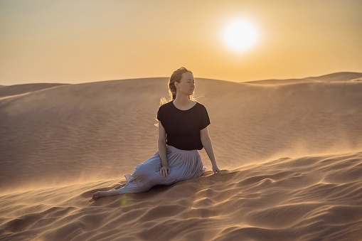 Young beautiful woman traveling in the desert. Sandy dunes and blue sky on sunny summer day. Travel, adventure, freedom concept. Tourism reopens after quarantine COVID 19.