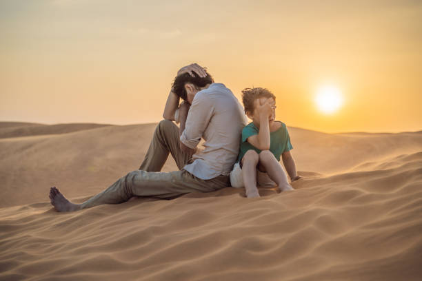 istock Relationship problems between father and son. Family conflict. Dad and son have a heated relationship, sit in the hot desert with their backs to each other and do not want to talk 1774101451
