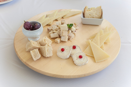 Spanish cheese assortment displayed on rotating tray. Rounded wooden display over table
