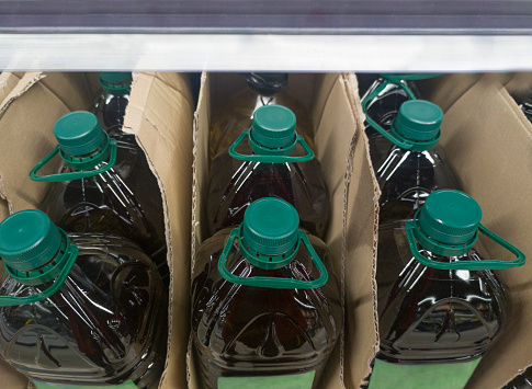 Extra virgin olive oil bottled and displayed on cardboard box at supermarket shelve. Overhead view