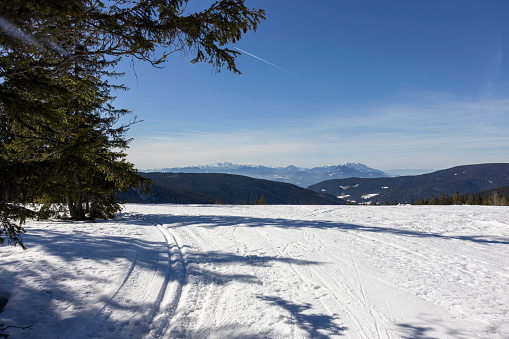 Scenic view of skiing track on winter landscape with mountain in distant against blue sky