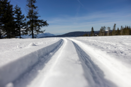 Scenic view of winter landscape with cross country ski tracks and mountain against blue sky