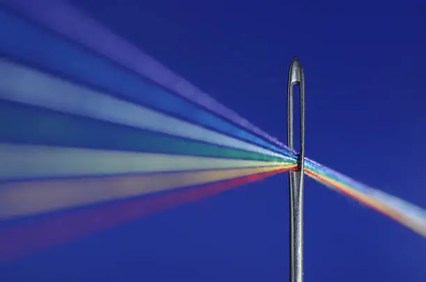 Colored threads passes through a needle's eye - symbolize refraction