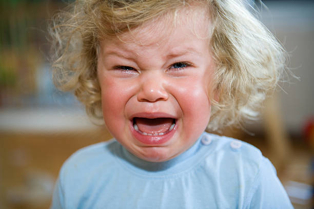 a child in a blue shirt that is crying - huilen stockfoto's en -beelden