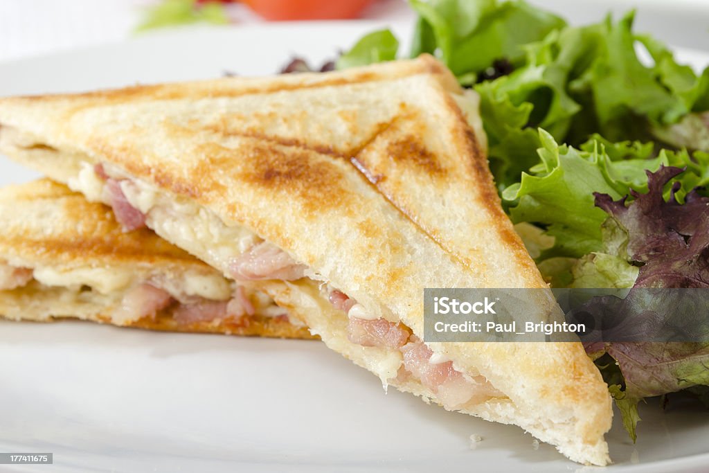 Cheese and Bacon Toastie Cheese and bacon pressed sandwich served with salad. Sandwich Stock Photo