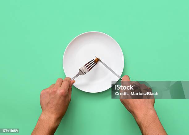 Knife And Fork Cutting Into Small Diet Meal On White Plate Stock Photo - Download Image Now