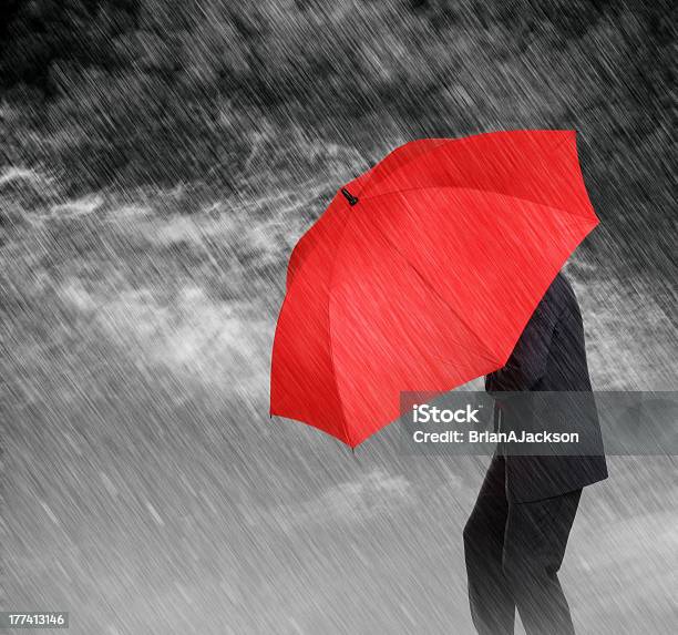 Businessman With A Red Umbrella Sheltering Himself From Rain Stock Photo - Download Image Now