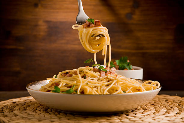 Pasta with carbonara Delicious spaghetti with bacon and egg called alla carbonara on wooden table spaghetti stock pictures, royalty-free photos & images