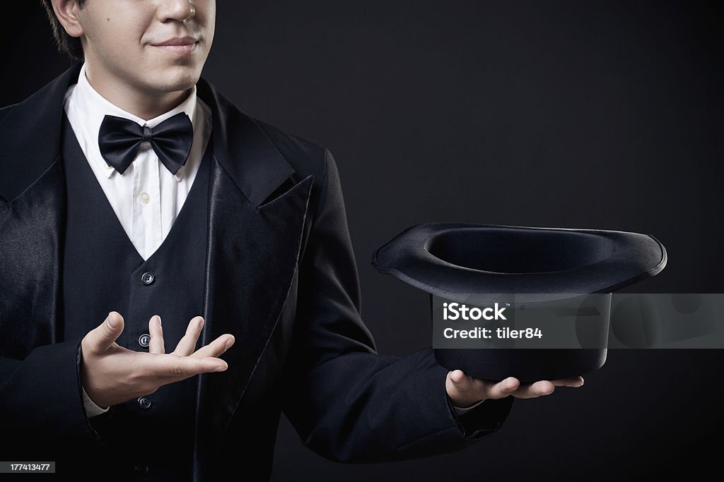 closeup of magician showing tricks with top hat isolated closeup of magician showing tricks with top hat isolated on dark background Magician Stock Photo