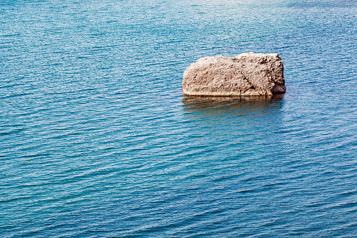 Stone rock standing alone in the sea close-up at day