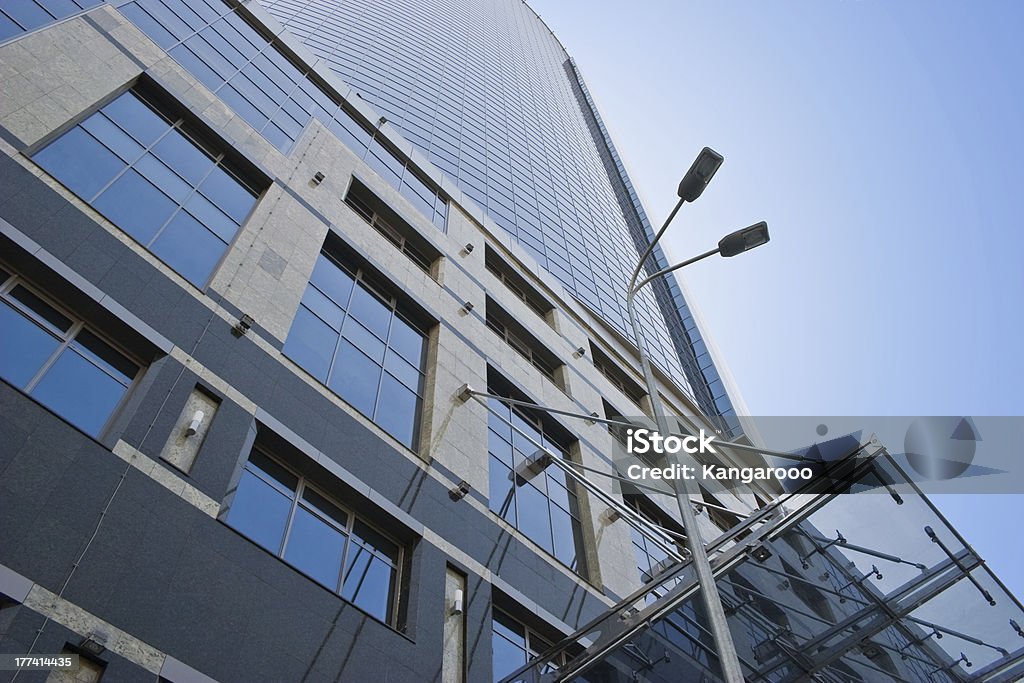 Skyscraper facade and street lamp Modern office building and street lamp against the clear blue sky - low angle view Architecture Stock Photo