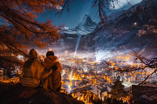 Romantic young couple looking at view on Zermatt and Matterhorn peak at winter night