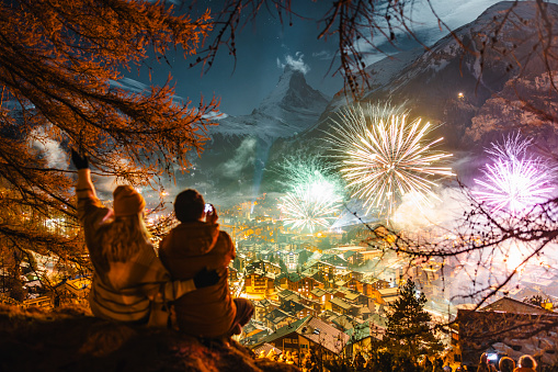 A couple sits and admires New Year fireworks above Zermatt and Matterhorn peak
