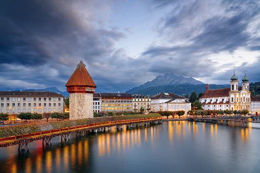 Lucerne, Switzerland with the Chapel Bridge over the River Reuss with Mt. Pilatus in the distance at dusk.