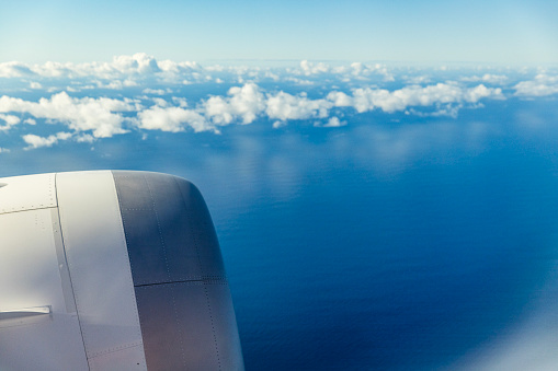 Looking out from airplane window to clouds and blue ocean