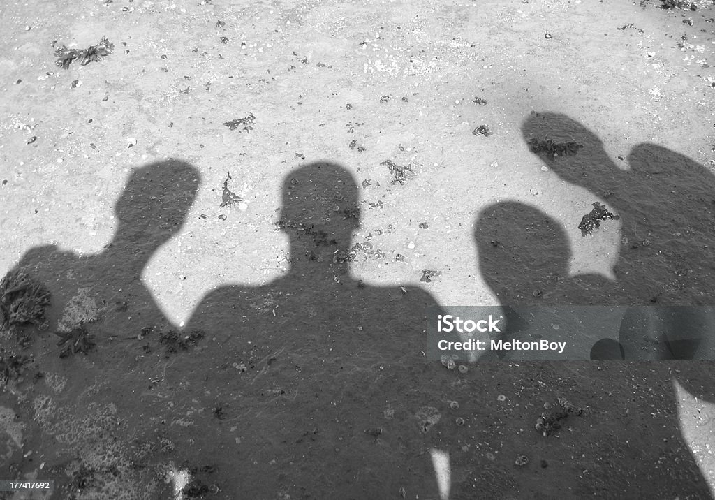 Four shadows Four connected shadows on a rocky beach Four People Stock Photo