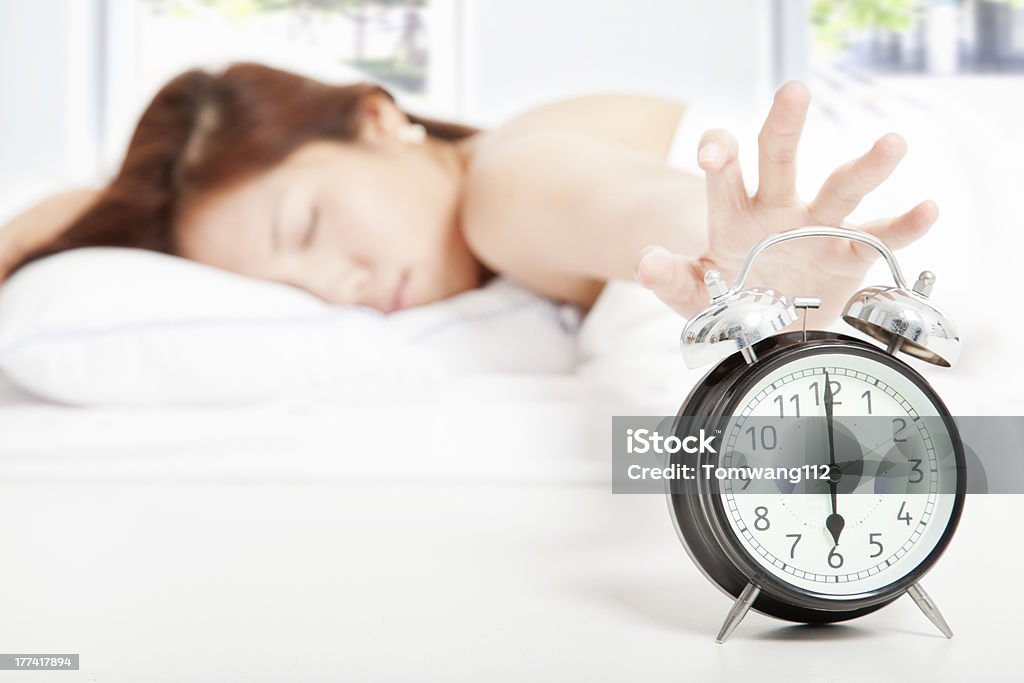 Woman turning off the alarm clock young Woman turning off the alarm clock Adult Stock Photo