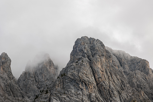 detailed view of a very steep rocky slope of a majestic mountain, seen from below, partially covered by the clouds. district of Sappada, F.V.G. region,Italy