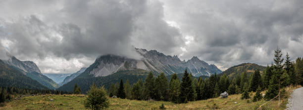 istock Wide panoramic composition with view on a beautiful and natural mountain environment in western Friuli Venezia Giulia, being covered by huge stormy cumulus clouds, during an autumn afternoon 1774186207