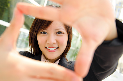 Smiling Asian business woman making a frame with fingers