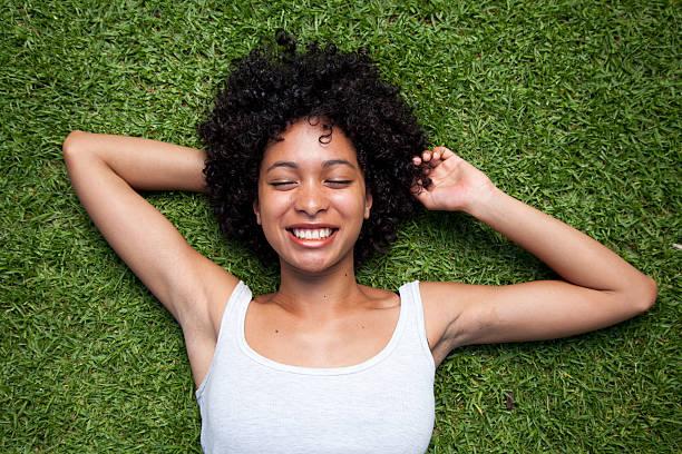 istock Young woman smiling while lying in the grass 177419597