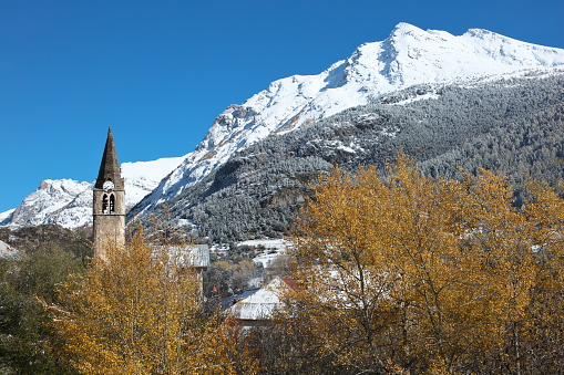 Photo taken in a north-northeast direction towards Brec Roux 3013m (to the right of the image) with the first significant snow falling at the beginning of November.\n\nThe bell tower of the Church of the Transfiguration of Our Lord built in the 19th century with the lateral movement of its stones at the top of the bell tower during an earthquake, the spire was broken...