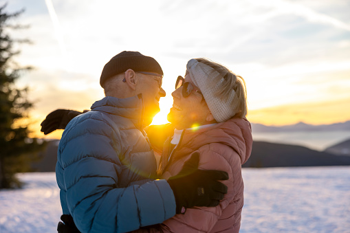 Happy senior couple embracing each other enjoying leisure time together at snowy winter landscape