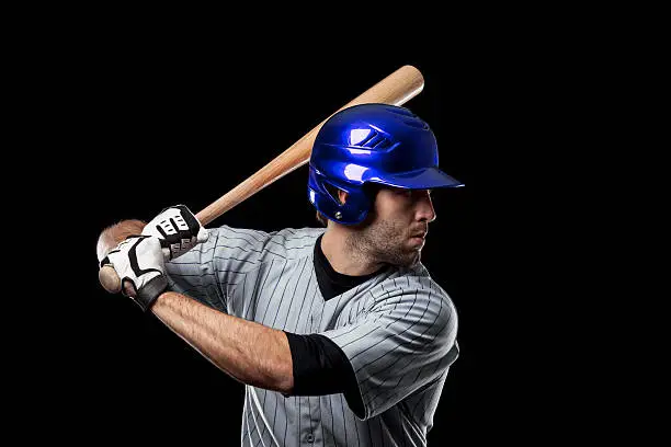 Baseball Player on a blue uniform on a black background. Studio Shot.