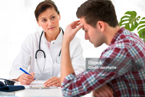 Female Doctor With Male Patient Who Is Holding His Head Stock Photo - Download Image Now