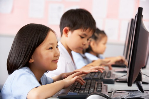 Female Pupil Using Keyboard During Computer Class In Chinese School Classroom