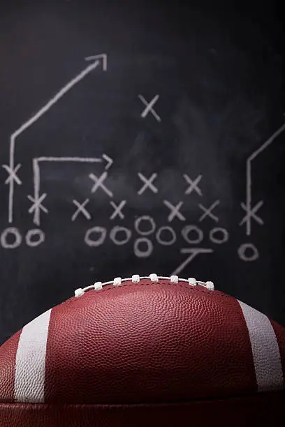 An American football and a hand drawn chalkboard play.