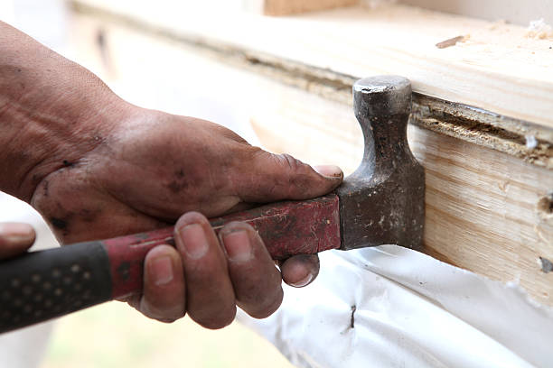 Worker Using Hammer To Pry Wood stock photo