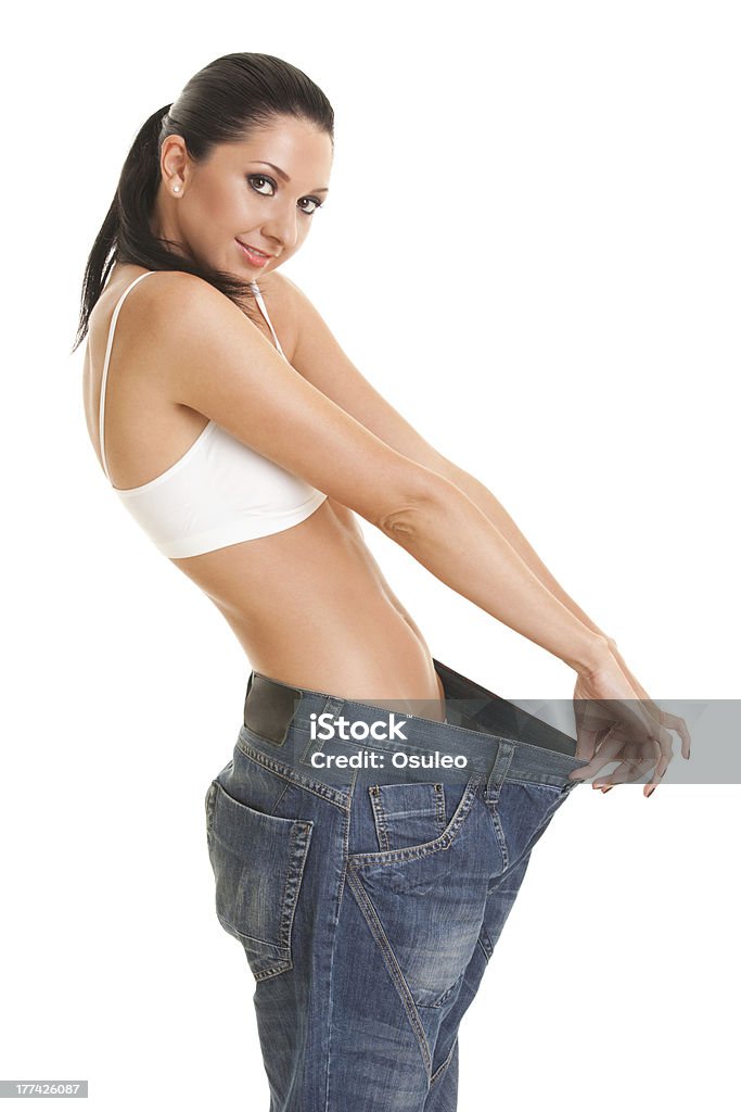 Woman shows her weight loss by wearing an old jeans "Funny woman shows her weight loss by wearing an old jeans, isolated on white background" Abdomen Stock Photo