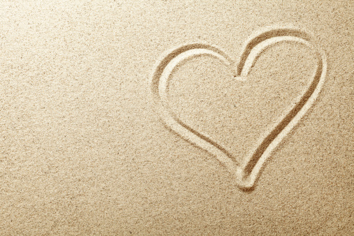 Heart drawn in the sand. Beach background. Top view