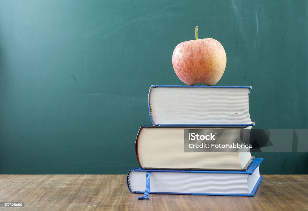 The fruit of wisdom Apple on a pile of books. In the background blank chalkboard. Space for text and graphics. Apple - Fruit Stock Photo