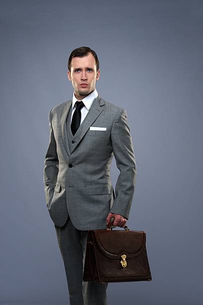 A businessman in a gray suit holding a suitcase stock photo