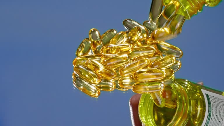 Close up of pouring fish oil vitamin gelatin capsules with Omega-3 on a blue background