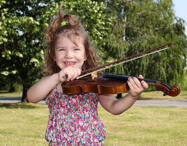 istock little girl with violin in park 177430169
