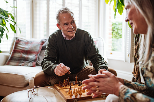 Two unrecognizable businessmen thinking over moves while playing chess against gray background