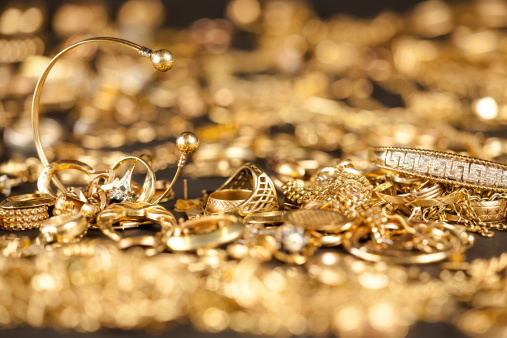 Table of scrap gold being inspected.Focal point on the two bracelets.