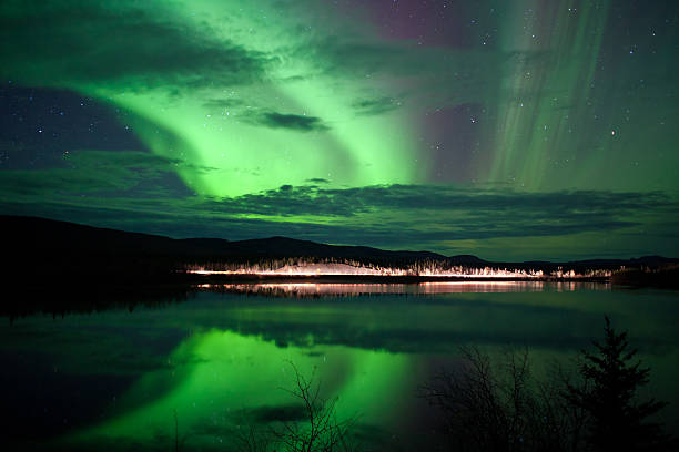 stars und northern lights über dunklen straße am see - yukon stock-fotos und bilder